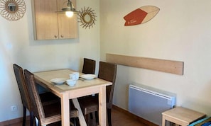 Ein Essbereich mit einem Holztisch, vier Stühlen und einem kleinen Beistelltisch.