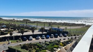 Vista costera con un estacionamiento, edificios y el mar al fondo.