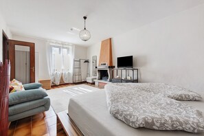 A bedroom with a bed, a TV, a fireplace, and a window with curtains.