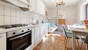 Une cuisine moderne avec des meubles blancs, une cuisinière à gaz et un coin repas comprenant une table et des chaises.