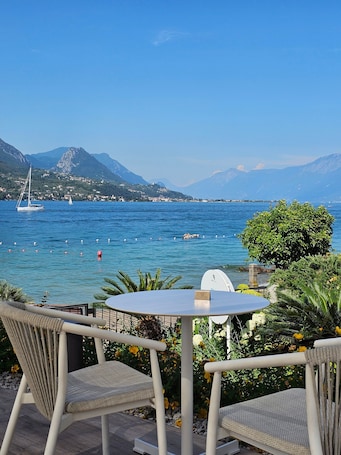A table and two chairs facing a body of water with boats and mountains in the background.. Holiday Home 'Puravida 4seasons - Nature Hideaway' with Mountain View, Terrace & Wi-Fi