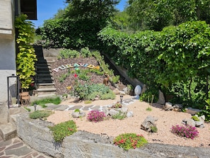 A garden with a stone pathway, a statue, and a sign reading 'PURA VIDA'. - Holiday Home 'Puravida 4seasons - Nature Hideaway' with Mountain View, Terrace & Wi-Fi (Provaglio Valsabbia)