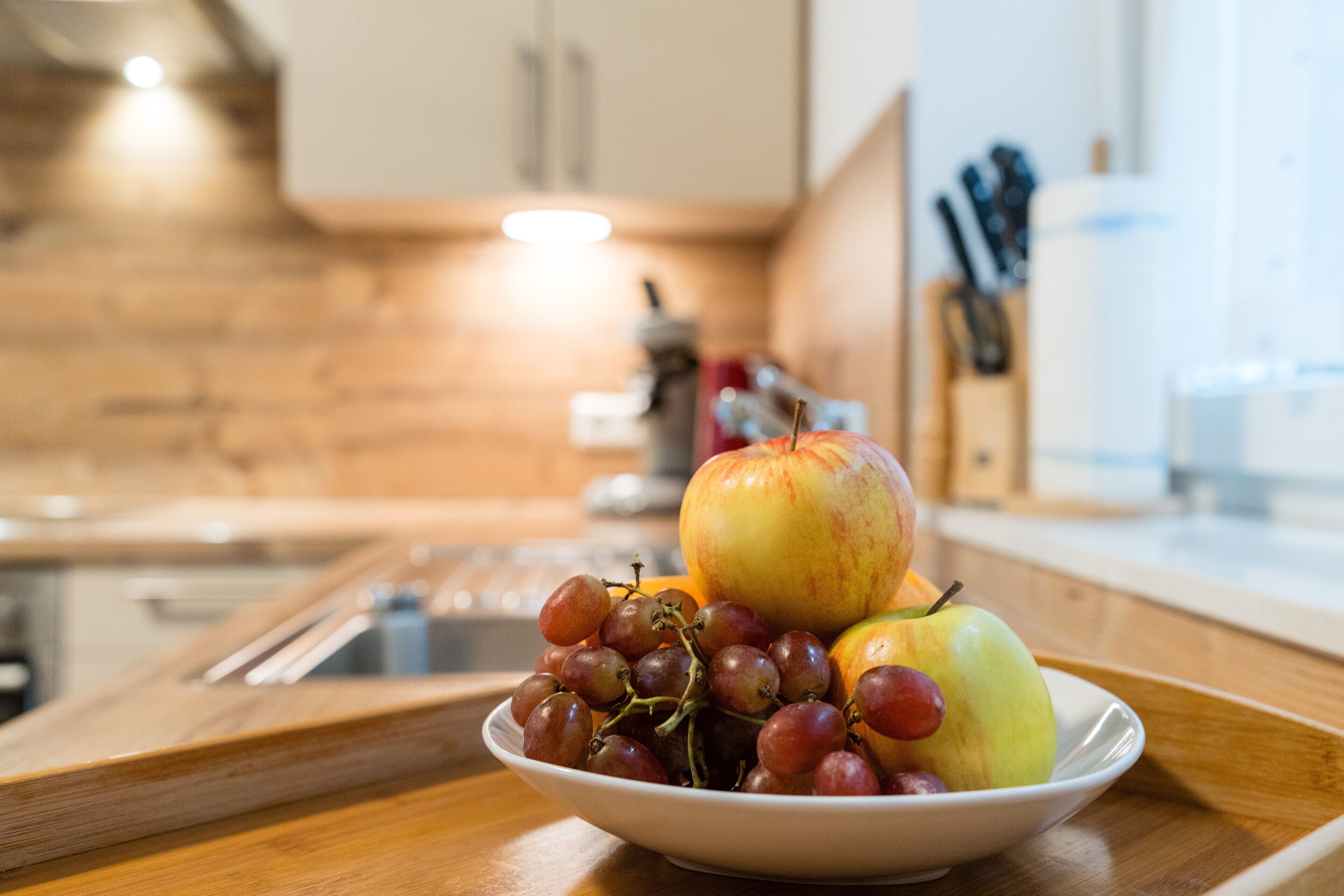 A bowl of fruit on a wooden surface in a kitchen.