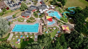 Vista aérea de un resort con una gran piscina, un tobogán acuático y un estacionamiento.
