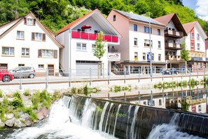 A multi-story building with balconies, a visible restaurant sign, and a waterfall in the foreground.