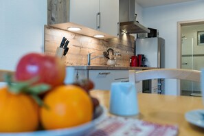 Eine moderne Küche mit Holzrückwand, Edelstahlgeräten und einer Obstschale auf dem Tisch.