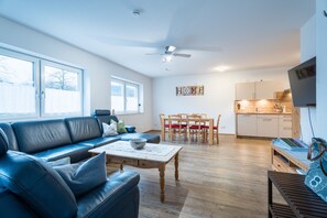 Ein modernes Wohnzimmer mit einer Couch, einem Couchtisch und einem Essbereich mit Stühlen und einem Tisch.