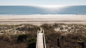 Une promenade en bois qui mène à une plage d’où l’on a une vue dégagée sur l’océan.