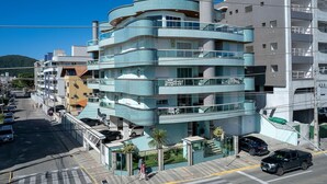 Un hotel a più piani con balconi, un'area di parcheggio e una vista aperta sulla strada.