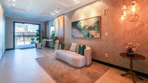 Una hall moderna con un divano, un tavolino con fiori, un quadro e una porta in vetro che dà sull'esterno.