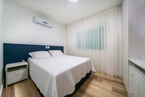 Una camera da letto ordinata con un letto, comodini e un condizionatore d'aria integrato.