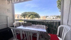 Ein Balkon mit Tisch und Stühlen, Blick auf Gebäude und Bäume, und ein Schild, das einen Ort kennzeichnet.