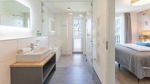 A modern hotel room with a large mirror, a sink, and a bed. - Luxusappartement auf Nordstrand (Nordstrand)