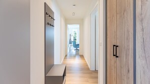 A modern hallway with wooden flooring, a bench, and a wooden wardrobe. - Luxusappartement auf Nordstrand (Nordstrand)