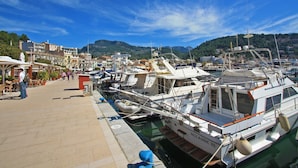 A marina with boats docked, a paved walkway, and buildings in the background. - Marina 48 Apartment on the Seafront with Sea Views, Wi-Fi and Air Conditioning (Port de Sóller)