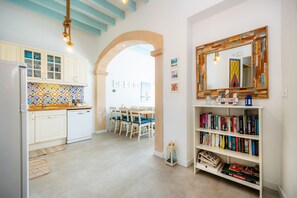 Een keuken met witte kasten, een betegelde spatwand en een eethoek met stoelen en een tafel.