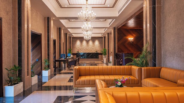 A modern lobby with a chandelier, leather seating, and a reception desk. - Jajati Courtyard (Korai)