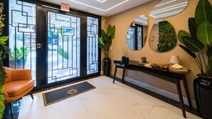 A modern hotel lobby with a reception desk, a large mirror, and a potted plant. - Duplex Alto Padrão Frente Mar c Piscina (Bombinhas)