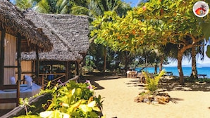 A beachside hut with a thatched roof, surrounded by lush greenery and a view of the sea. - Djema Forest (Nosy Be)