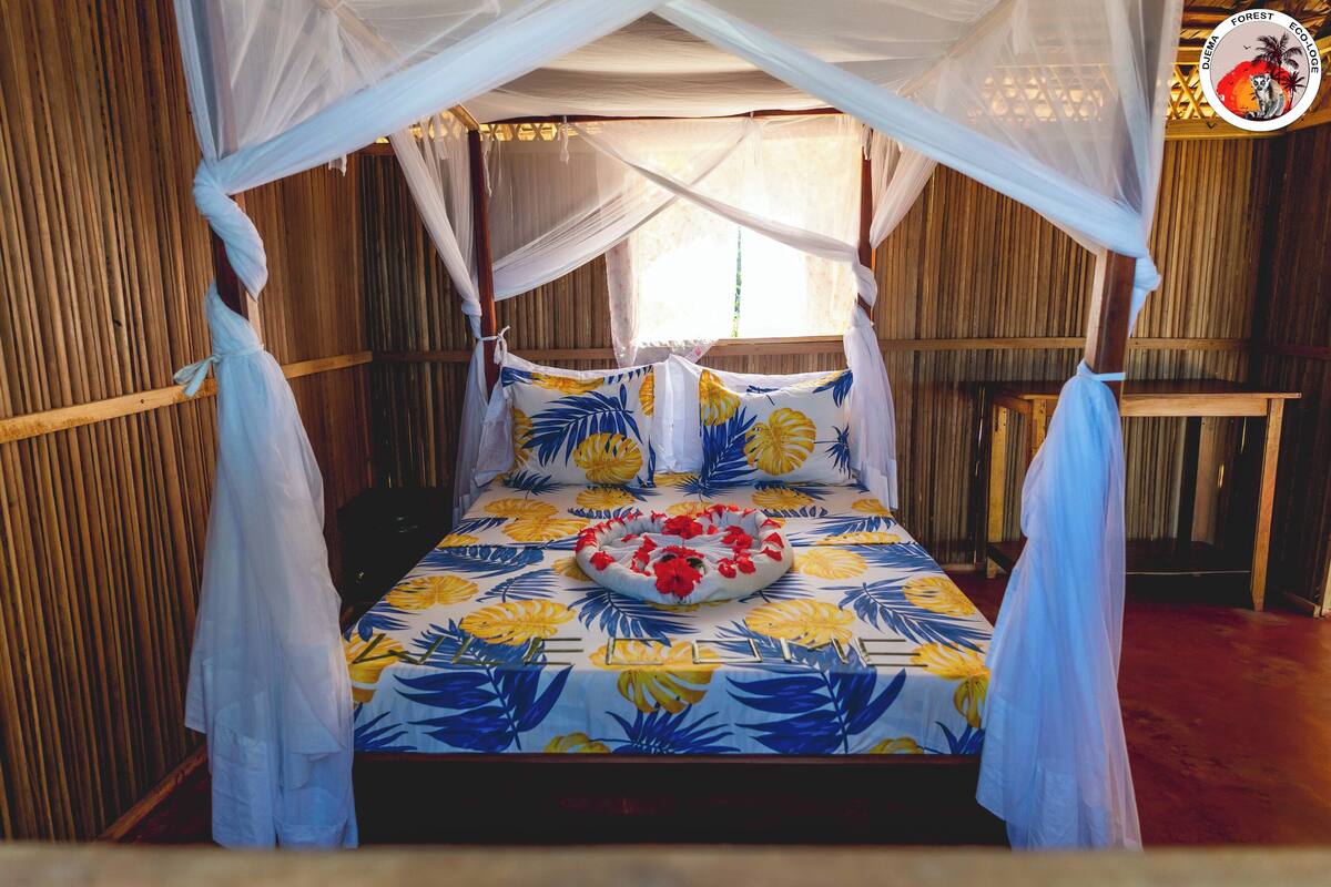 A bed with a canopy, a floral bedspread, and a circular rug.