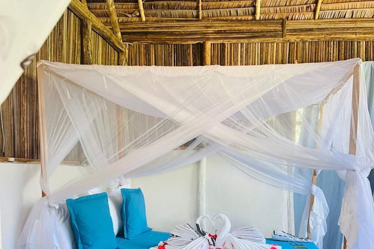 A bed with a blue mattress, white pillows, and a canopy.