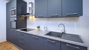 A modern kitchen with dark cabinets, a stainless steel sink, and built-in appliances including an oven and microwave. - Great 1-Bedroom Apartment in Trpanj - Pelješac (Trpanj)