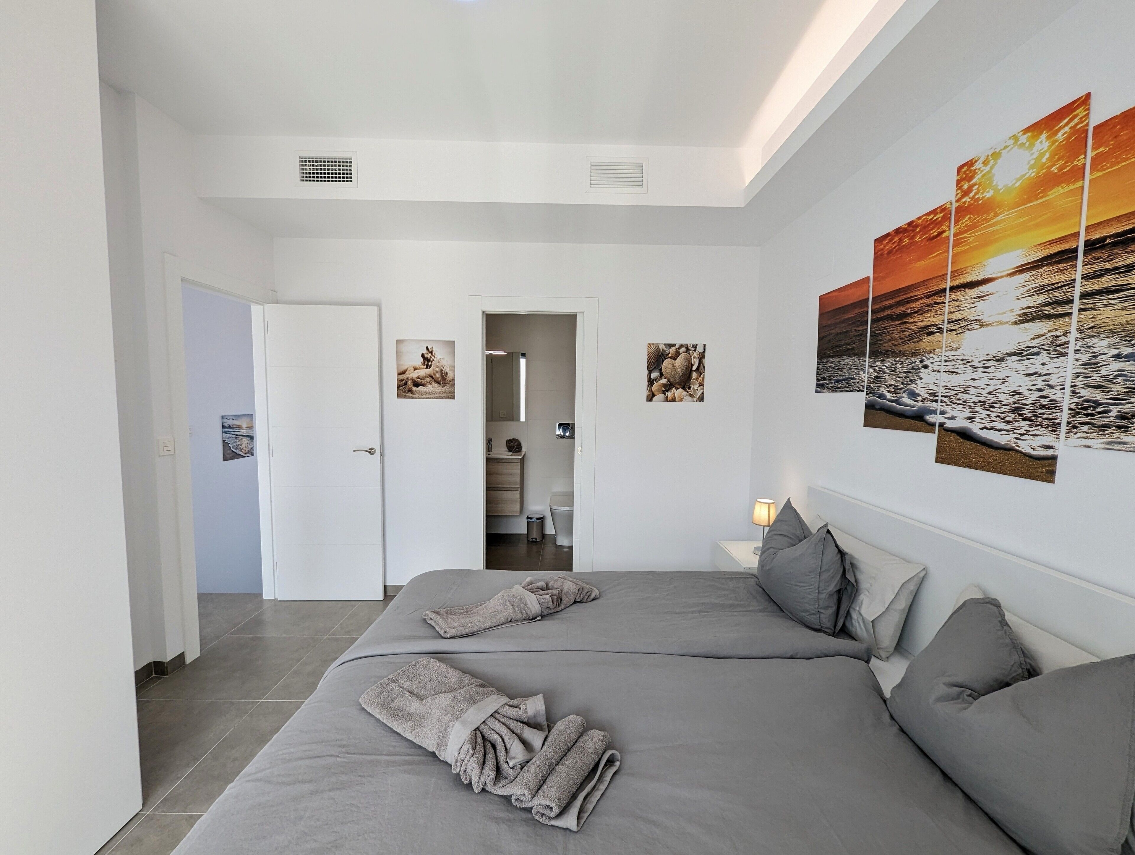 Una camera da letto moderna con un letto grande, due comodini, un tavolino e una lampada a parete.