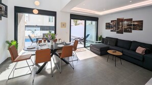 A modern living space with a dining area, a sofa, and a large window. - Villa 'R-58 Luxury New Build' with Private Pool, Terrace and Wi-Fi (Los Montesinos)