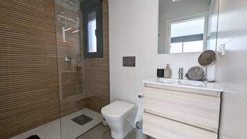 A modern bathroom with a glass shower enclosure, a toilet, a sink with a mirror, and a towel rack.