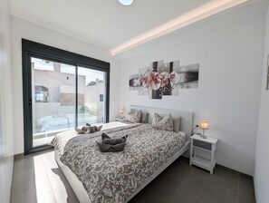 A modern bedroom with a large bed, a glass door leading to a balcony, and a wall-mounted artwork. - Villa 'R-58 Luxury New Build' with Private Pool, Terrace and Wi-Fi (Los Montesinos)