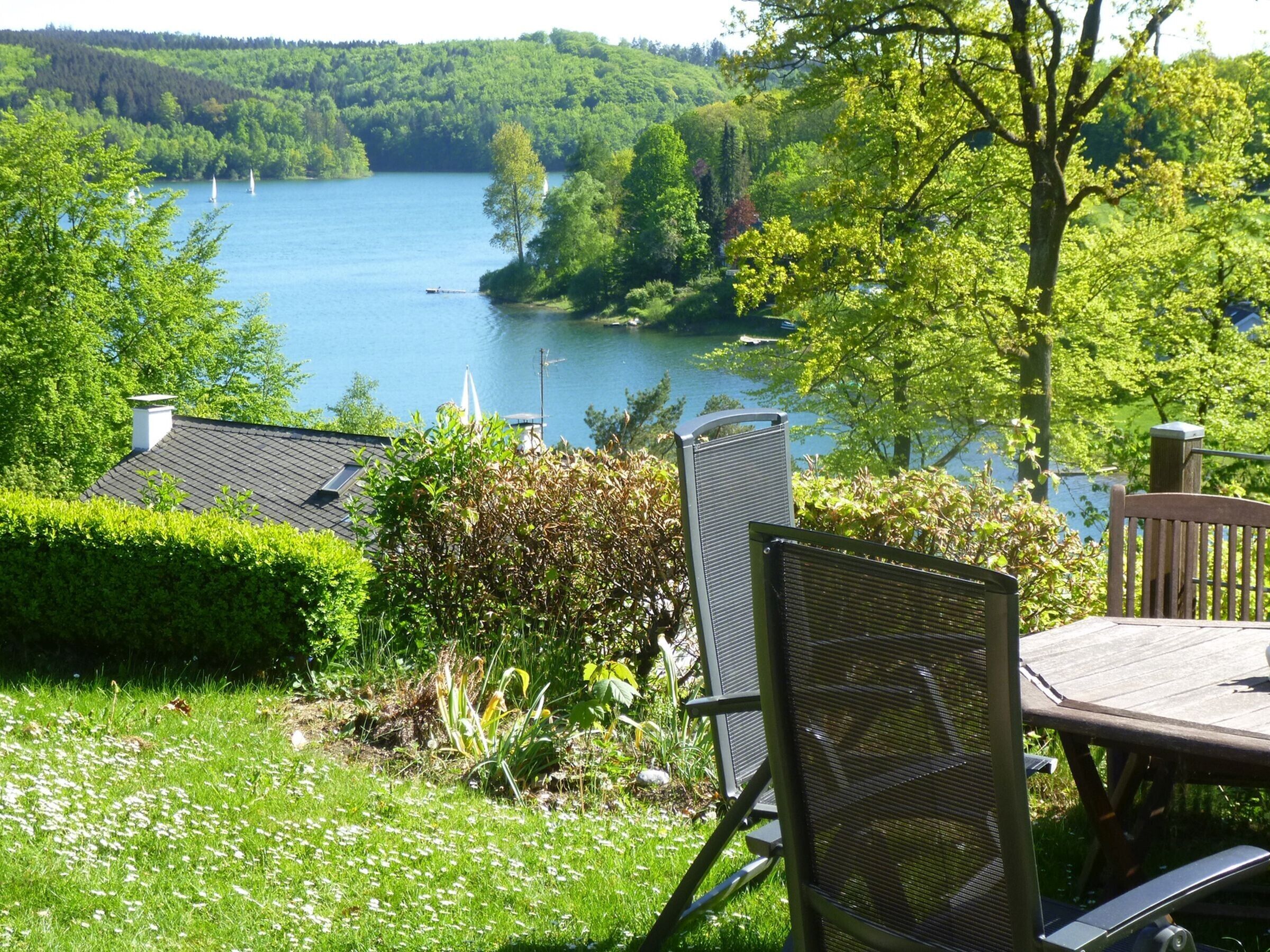 A lakeside view with a dining area, chairs, and a table.