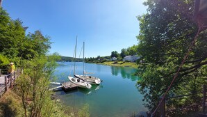 A calm lake with boats docked, surrounded by greenery and houses. - Panorama Holiday Home Sorpesee, 120 sqm, Lake View, Private Terrace & Wi-Fi (Sundern)