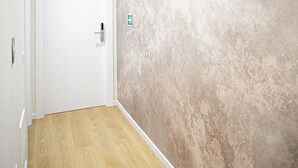 A hallway with a wooden floor, a white door, and a textured wall. - Cozy and spacious suite near Vatican with private bathroom (Room 3) (Roma)