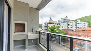 A balcony with a built-in sink, a view of the street, and a mountain in the background. - Sunny Flats 103 - Piscina Bombinhas (Bombinhas)