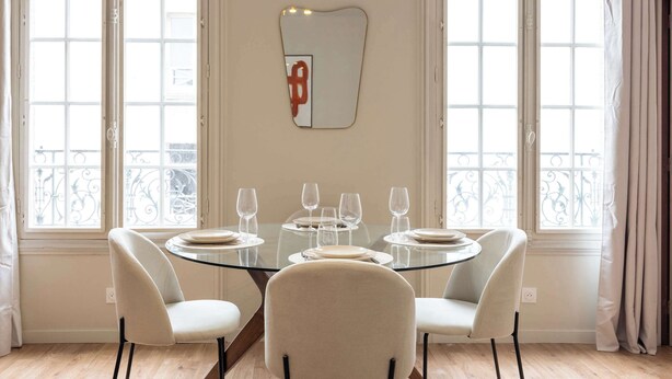 A dining area with a round glass table, four chairs, and a decorative mirror on the wall. - Elegant, fully equipped, air-conditioned accommodation (Le Pré-Saint-Gervais)