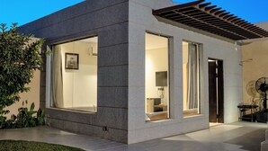 A modern house with large windows, a covered patio, and a well-maintained lawn. - The Corner Resort (Riyadh)