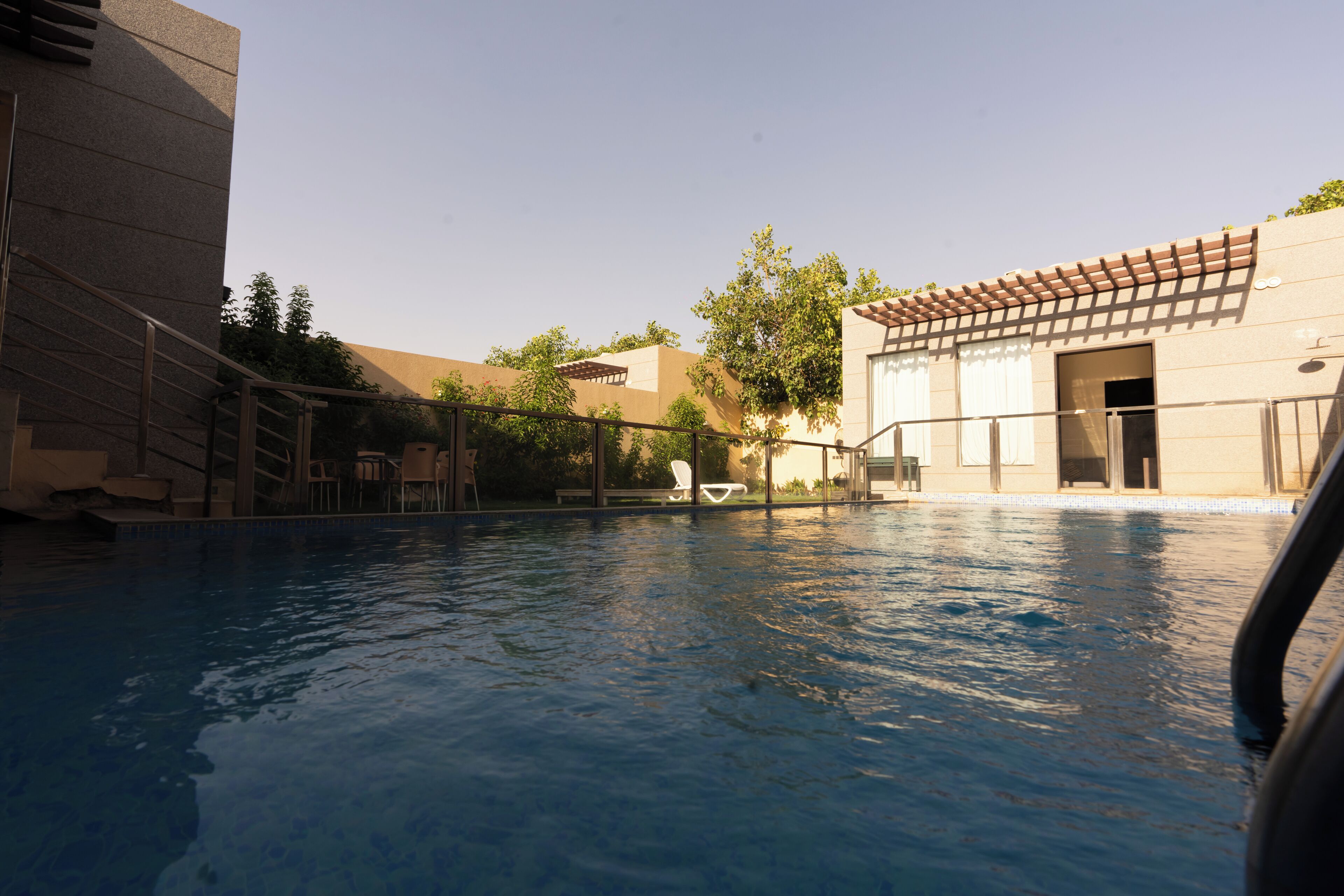 A swimming pool with a clear view of the surrounding buildings and a few lounge chairs.