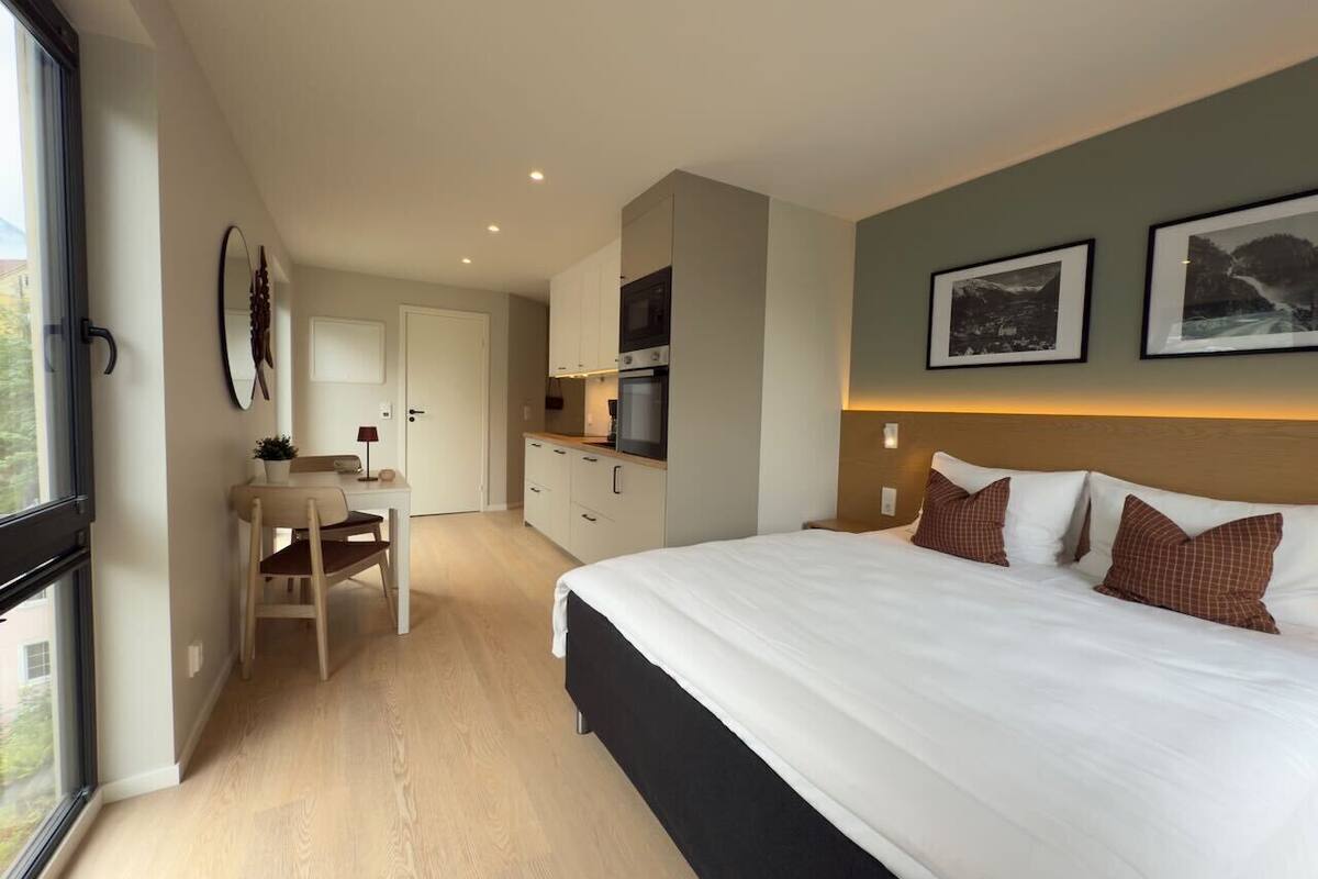 Une chambre d’hôtel moderne équipée d’un grand lit, d’un bureau et d’une kitchenette.