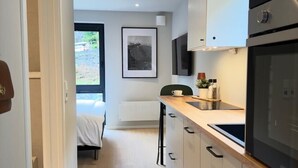 A modern kitchen with a wooden countertop, stainless steel appliances, and a view to the outside.