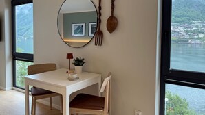 A dining area with a table, chairs, a mirror, and a view of a body of water.