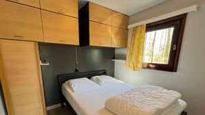 Ein Schlafzimmer mit Bett, Holzschrank und einem fenster mit Vorhängen.