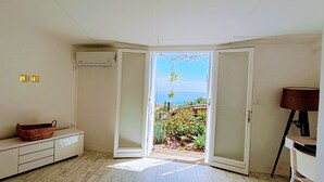 Una habitación con puerta corredera que da a un balcón con vistas al mar.