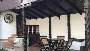 An outdoor patio with a round table and chairs, stone steps, and a wooden fence. - Lele Maria's Cottage (Arpașu de Sus)