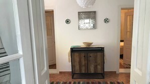 A hallway with a wooden cabinet, a colorful striped rug, and a decorative wall piece. - Lele Maria's Cottage (Arpașu de Sus)