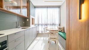 Une cuisine moderne avec des armoires blanches, un four encastré et un coin repas comprenant une table et des chaises en bois.