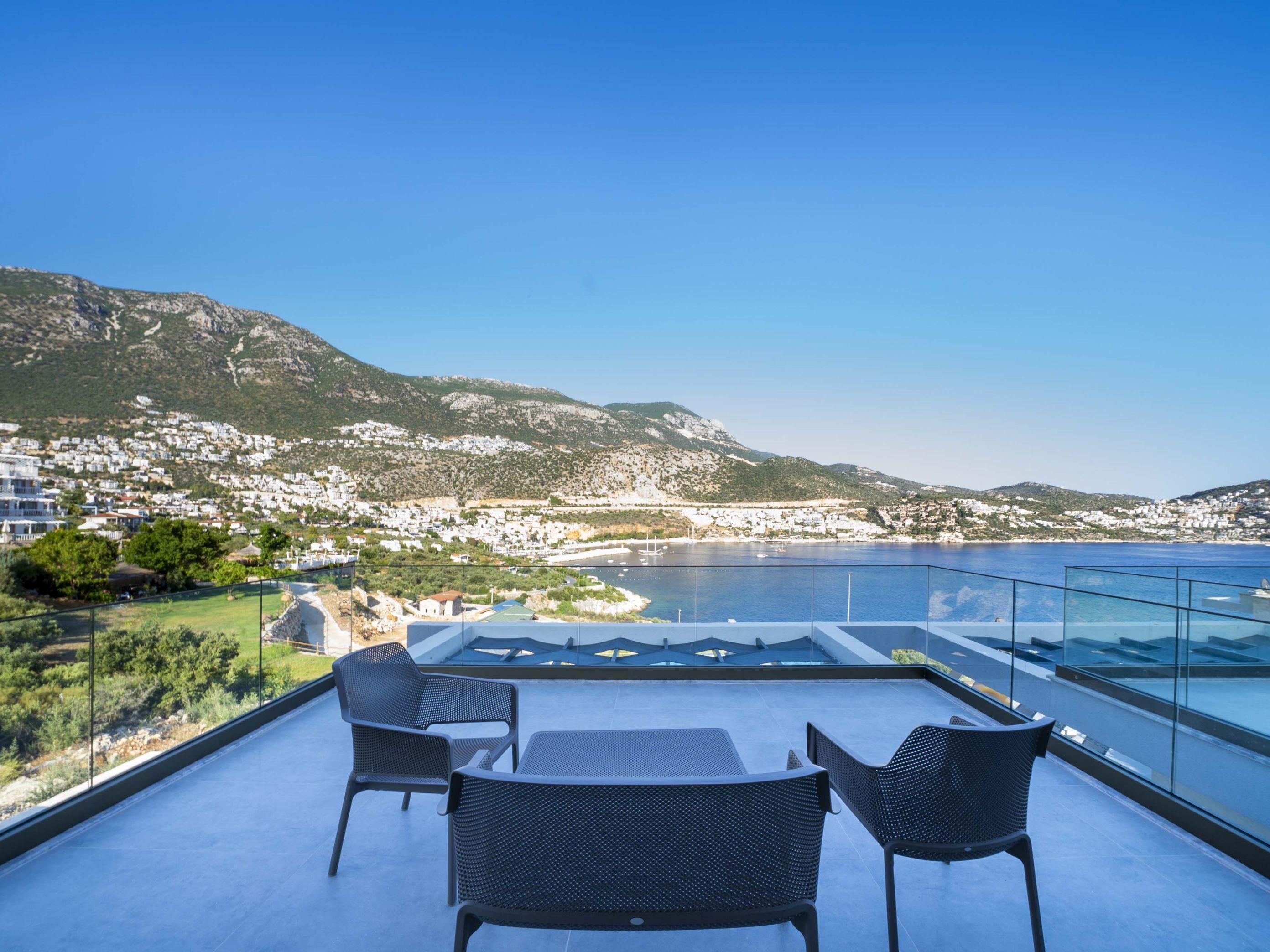 A rooftop terrace with a clear view of a coastal town and mountains.