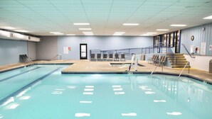 Une grande piscine intérieure avec des couloirs bien délimités, un espace vestiaire et un escalier menant à un niveau supérieur.