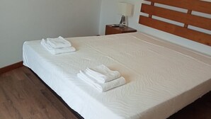 Ein ordentlich bezogenes Bett mit weißen Leinen und zwei gefalteten Handtüchern.
