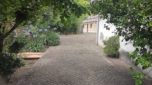 Ein Kopfsteinpflasterweg führt zu einem Gebäude mit weißer Fassade und roter Tür.