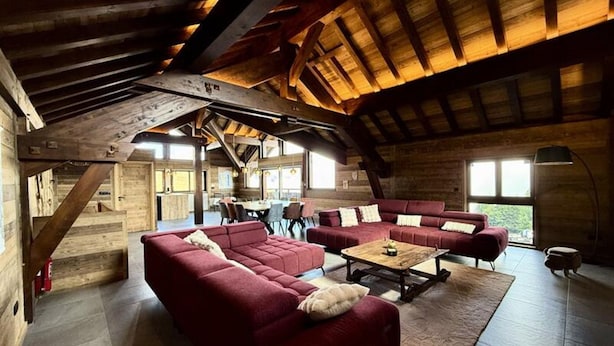 Ein Innenraum mit Holzbalken, einem Essbereich und roten Sofas.